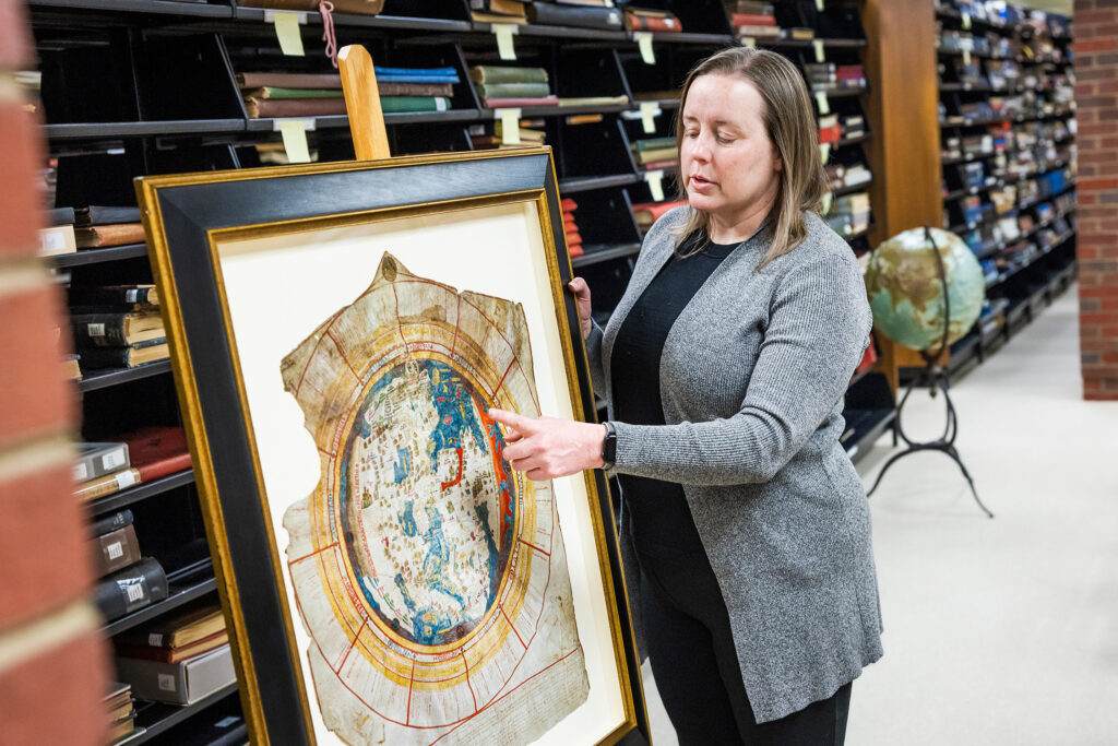 Photo of Marcy Bidney, curator of the American Geographical Society Library, pointing to details on the Leardo Mappamundi, a map of the world hand-drawn in 1452. (UWM Photo/Elora Hennessey)