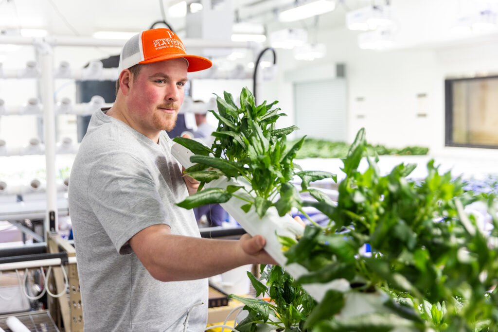 Photo of UW-Platteville student Brock Stringfield carefully tending to the spinach in the hydroponics lab, ensuring it’s ready for harvest after weeks of growth. (Photo credit: UW-Platteville)
