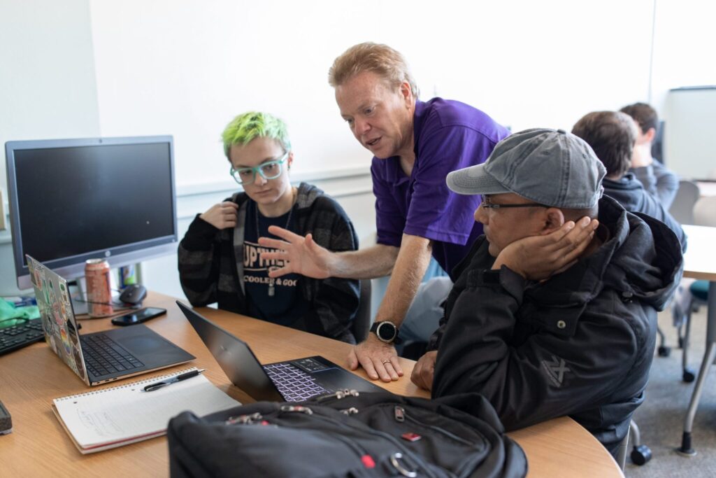 Photo of professor and students: UW-Stevens Point's new undergraduate artifical intelligence program looks to blend skills in programming with knowledge of the technical and ethical aspects of AI development.